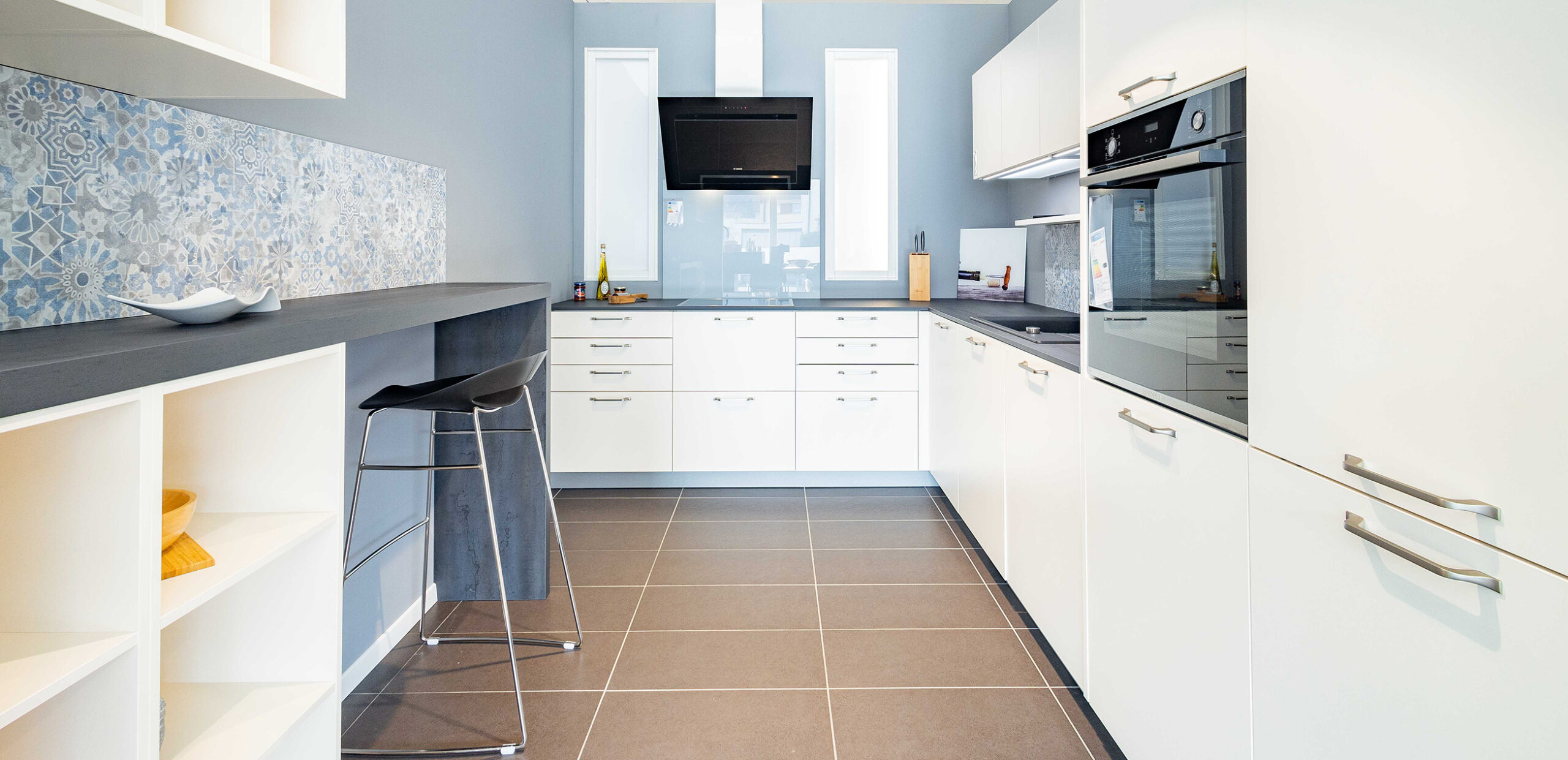 Klassische helle Küche mit grauer Arbeitsplatte und Sitzgelegenheit