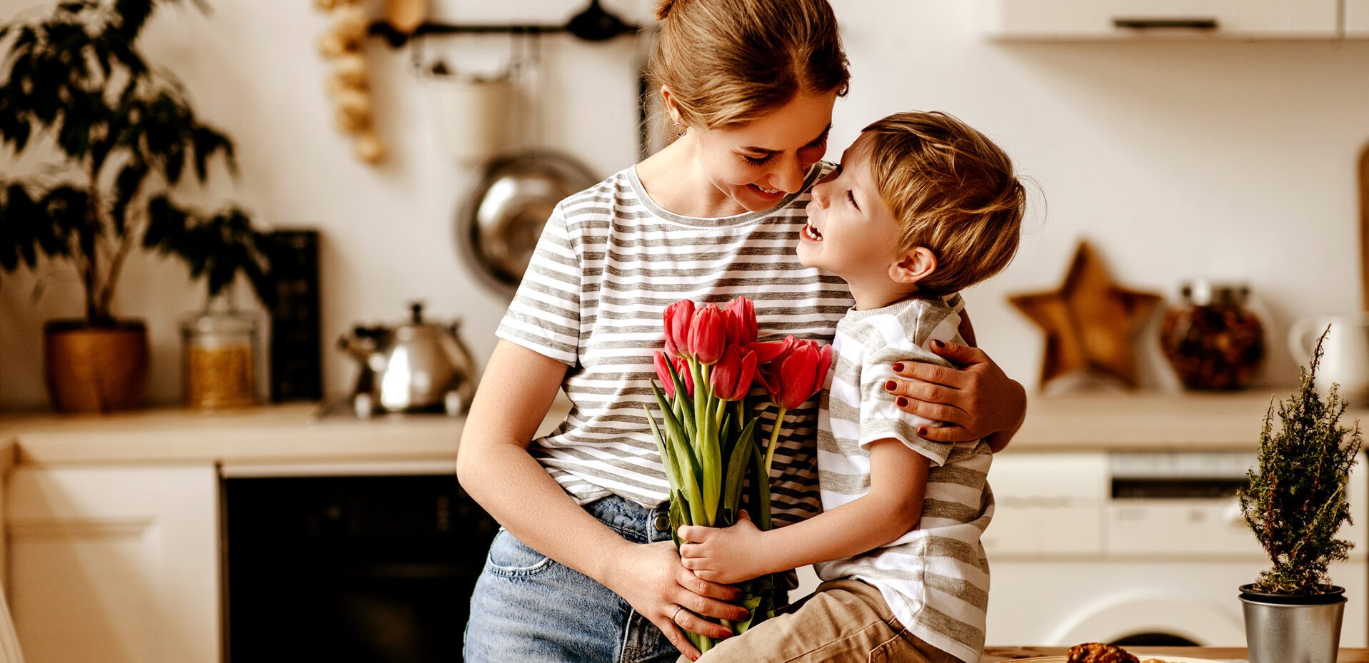 Mutter mit Kind in der Küche mit roten Tulpen in der Hand